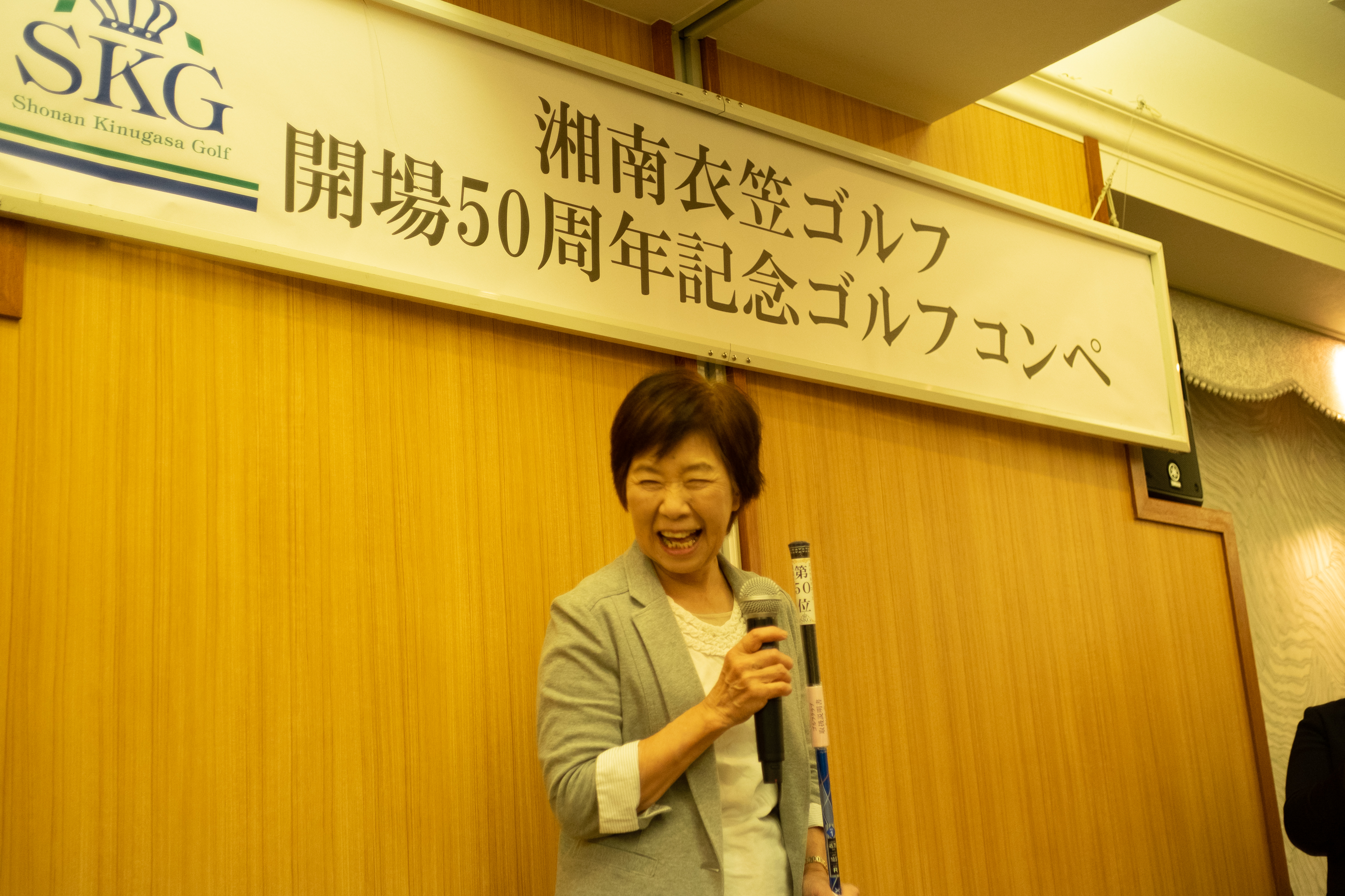 ゴルフコンペで表彰される女性