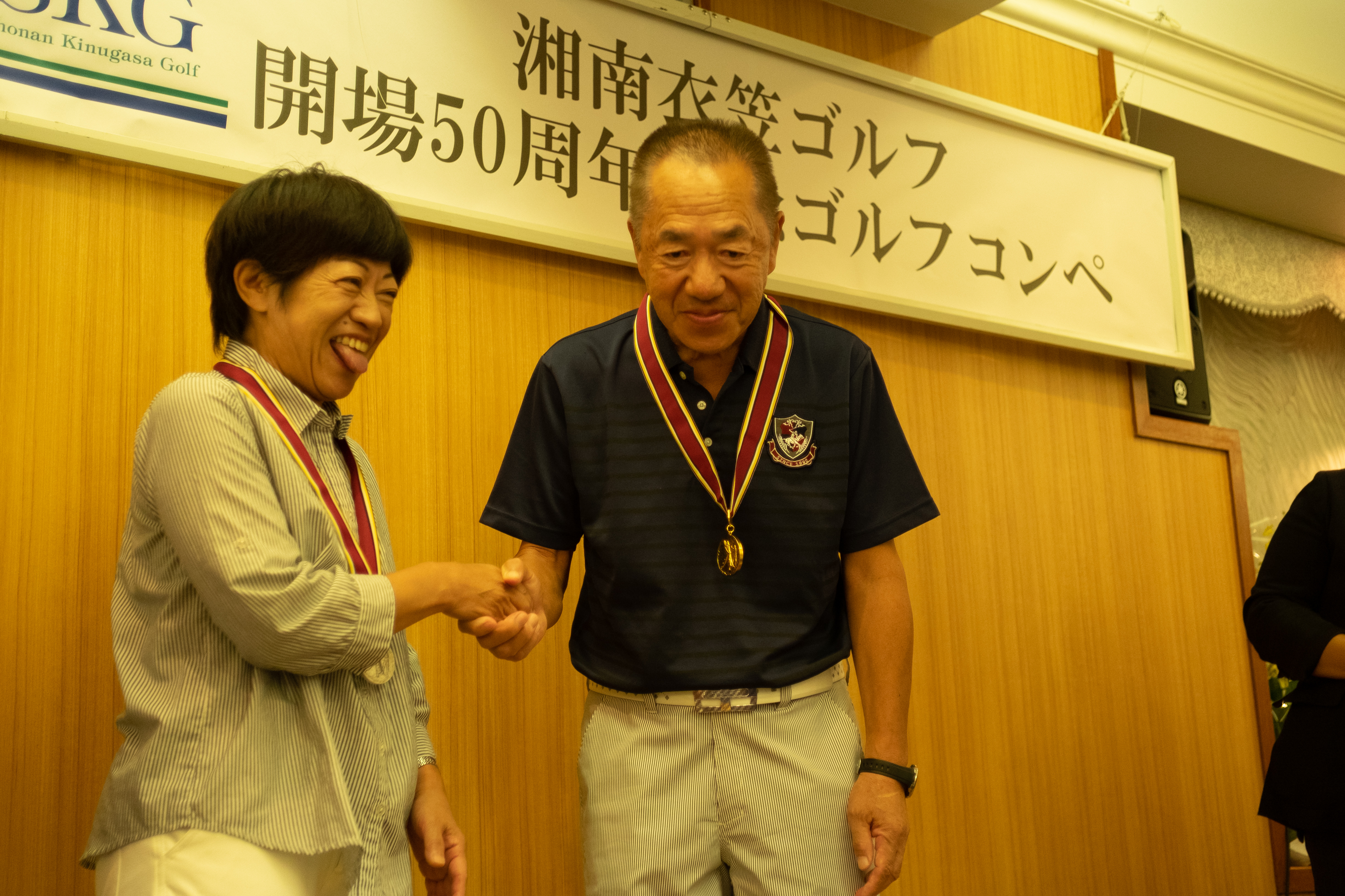 ゴルフコンペで表彰される夫婦