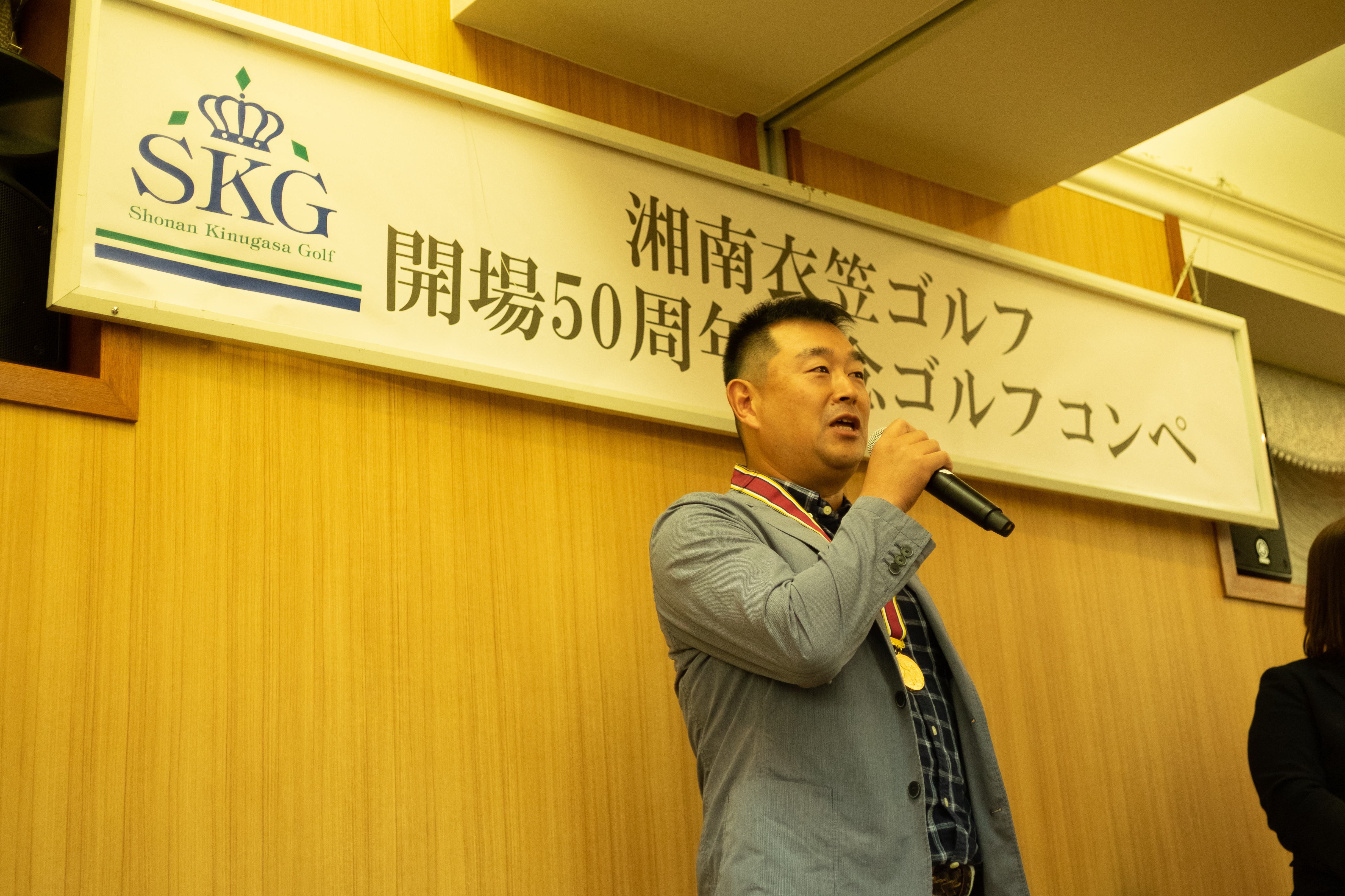 ゴルフコンペで表彰される男性